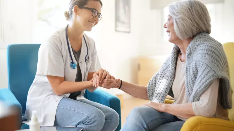 Doctor reassuring older woman in modern clinic                              